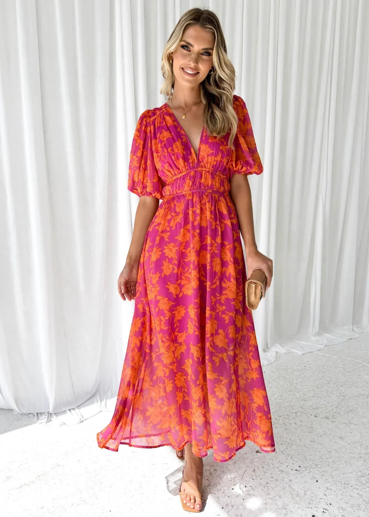 Woman modeling vibrant floral midi dress with V-neck and puff sleeves.