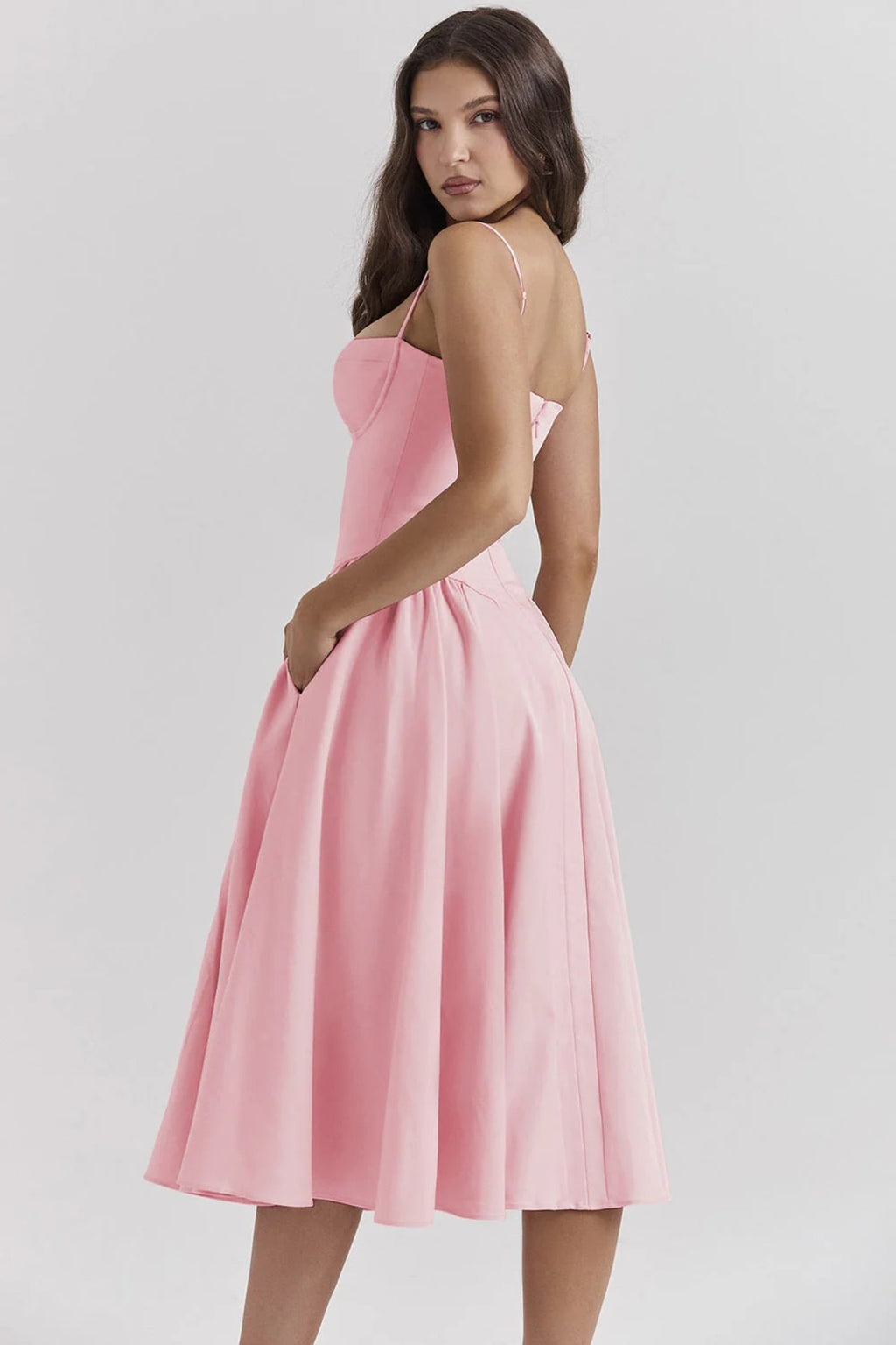 Woman wearing a bustier midi dress with spaghetti straps and A-line skirt.