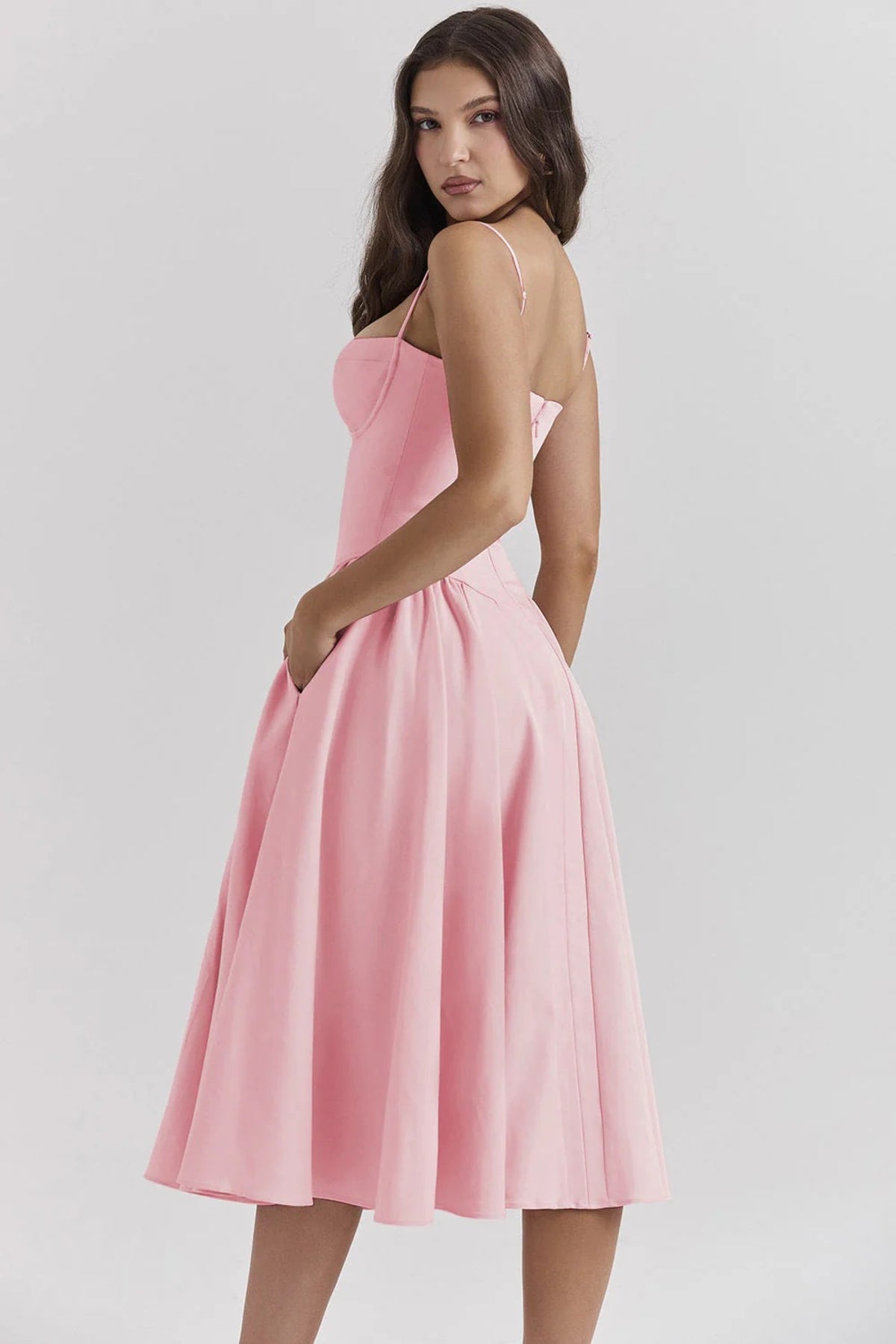Woman wearing a bustier midi dress with spaghetti straps and A-line skirt.