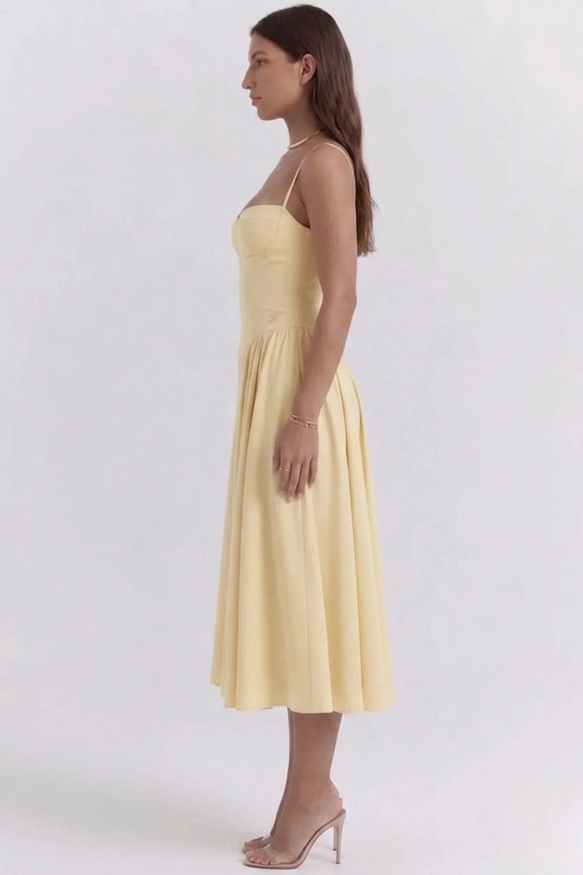 Woman wearing a bustier midi dress with spaghetti straps and A-line skirt.