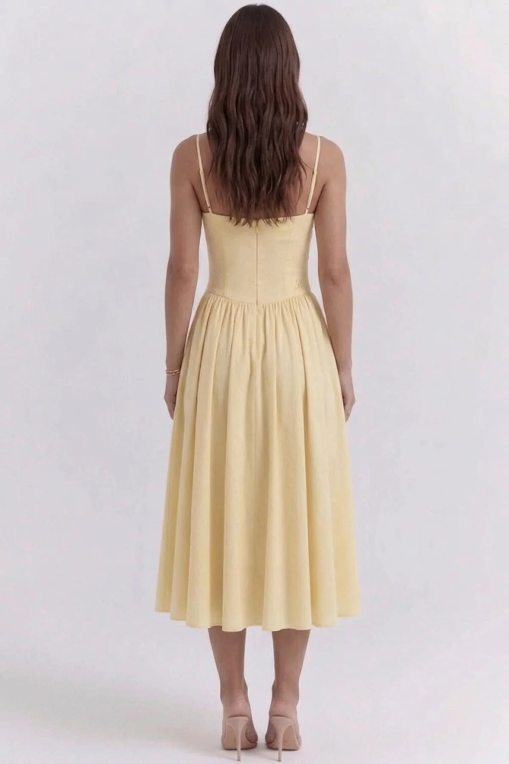 Woman wearing a bustier midi dress with spaghetti straps and A-line skirt.