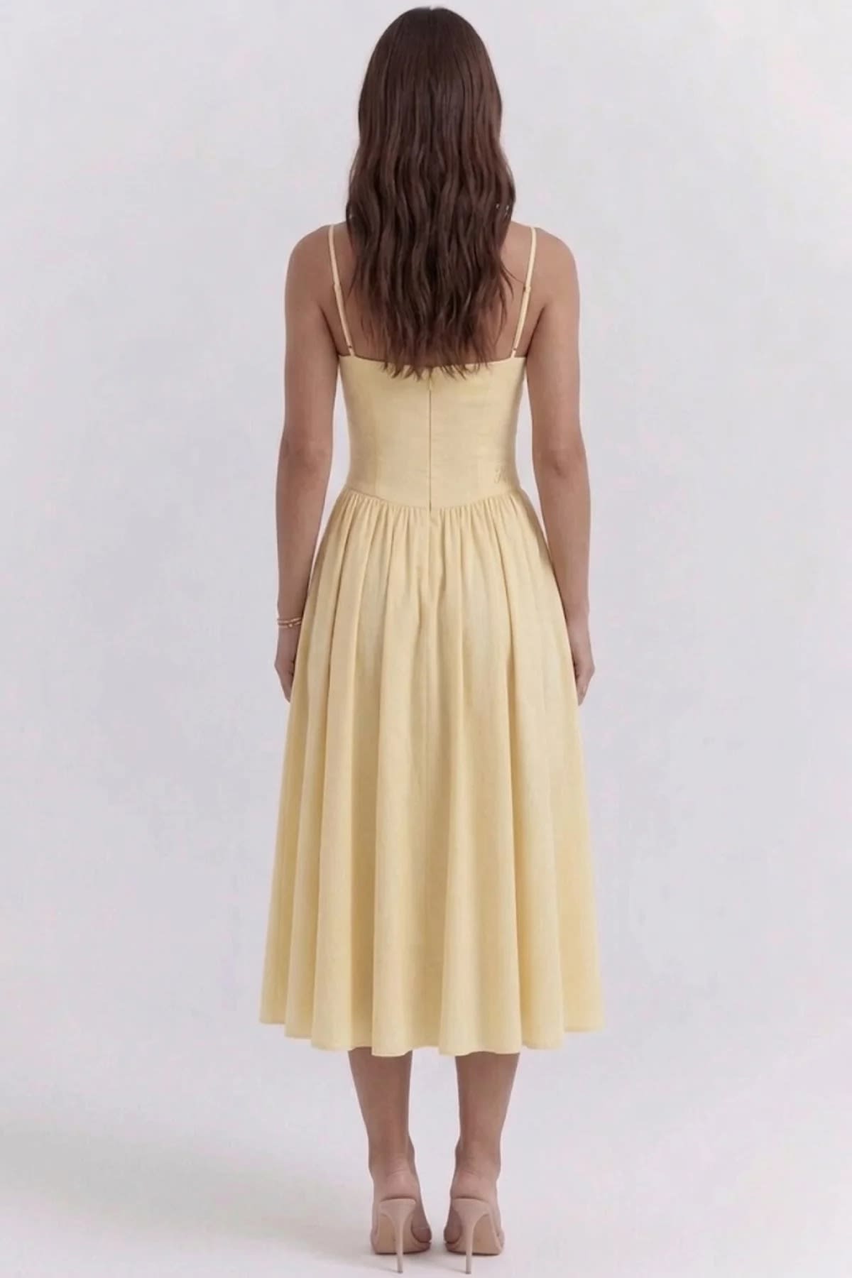 Woman wearing a bustier midi dress with spaghetti straps and A-line skirt.