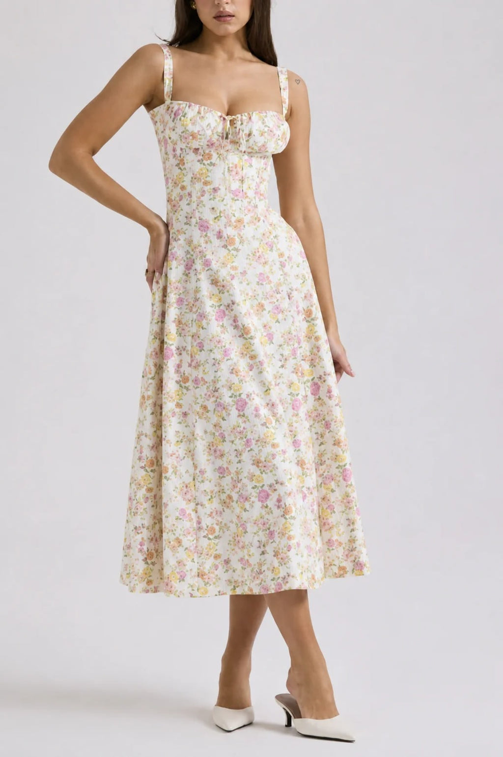 Woman wearing white midi dress with floral pattern and sweetheart neckline.