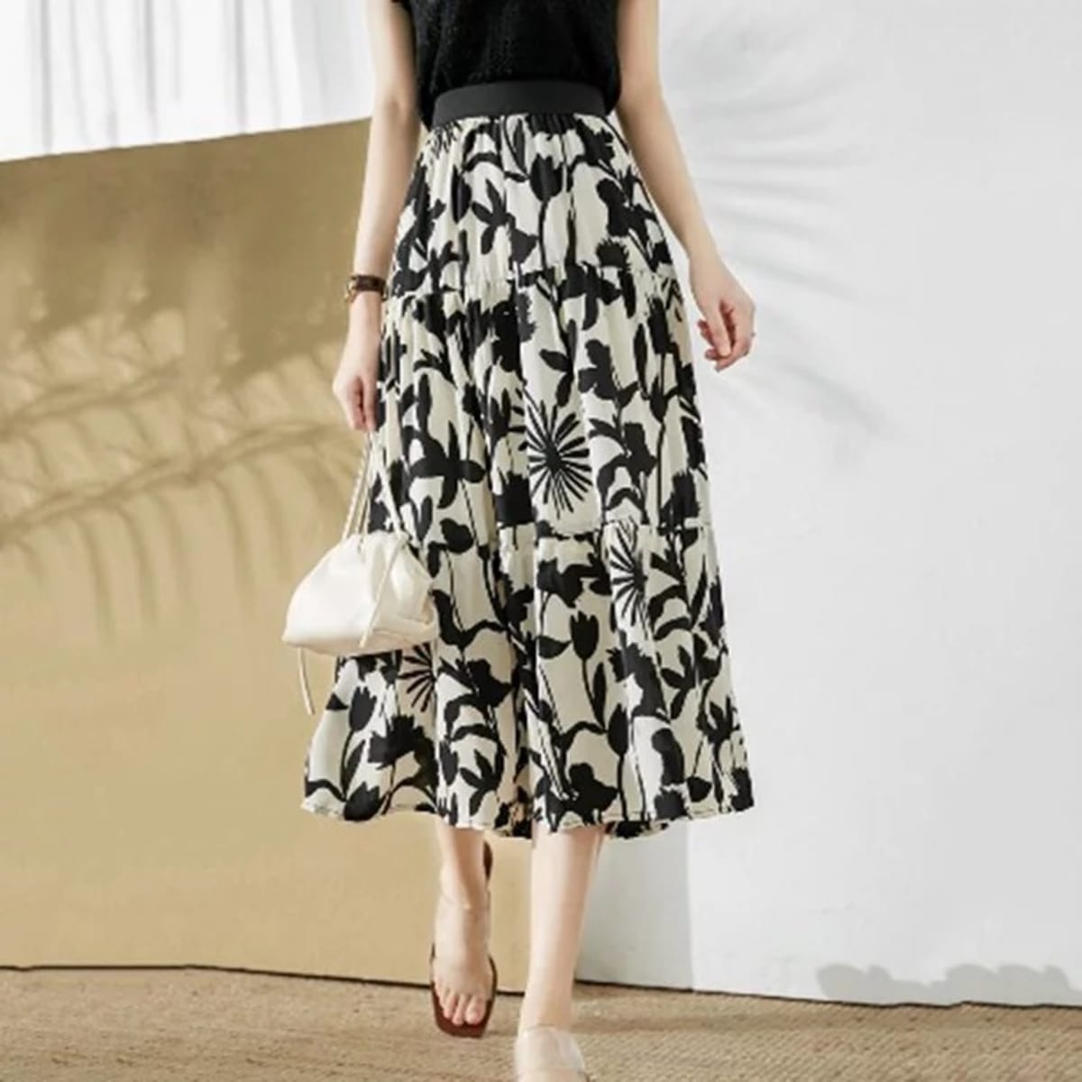 Woman wearing a floral tiered a-line midi skirt with sleeveless top.