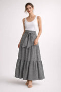 Woman wearing gingham tiered maxi skirt with tie-waist.