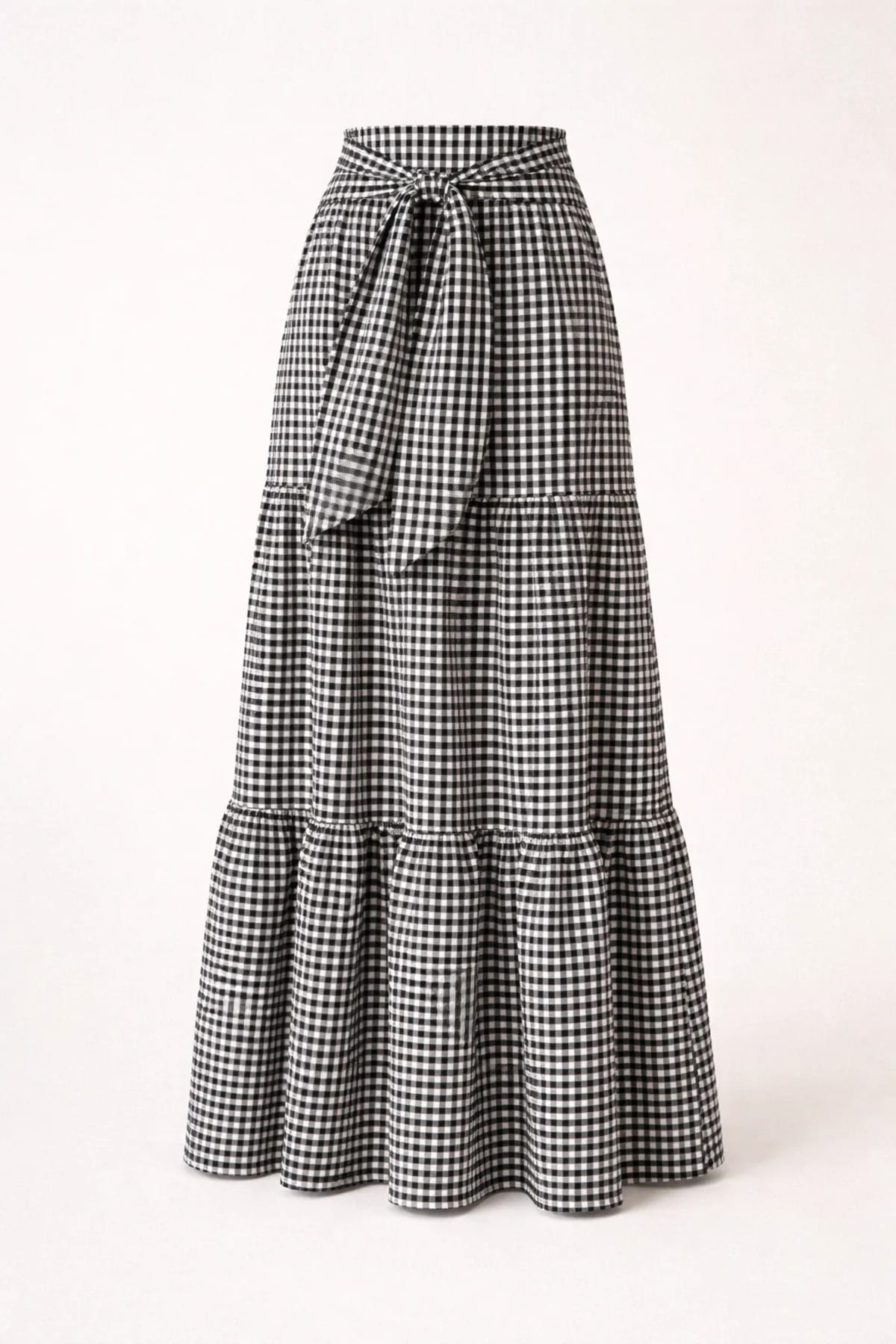 Woman wearing gingham tiered maxi skirt with tie-waist.