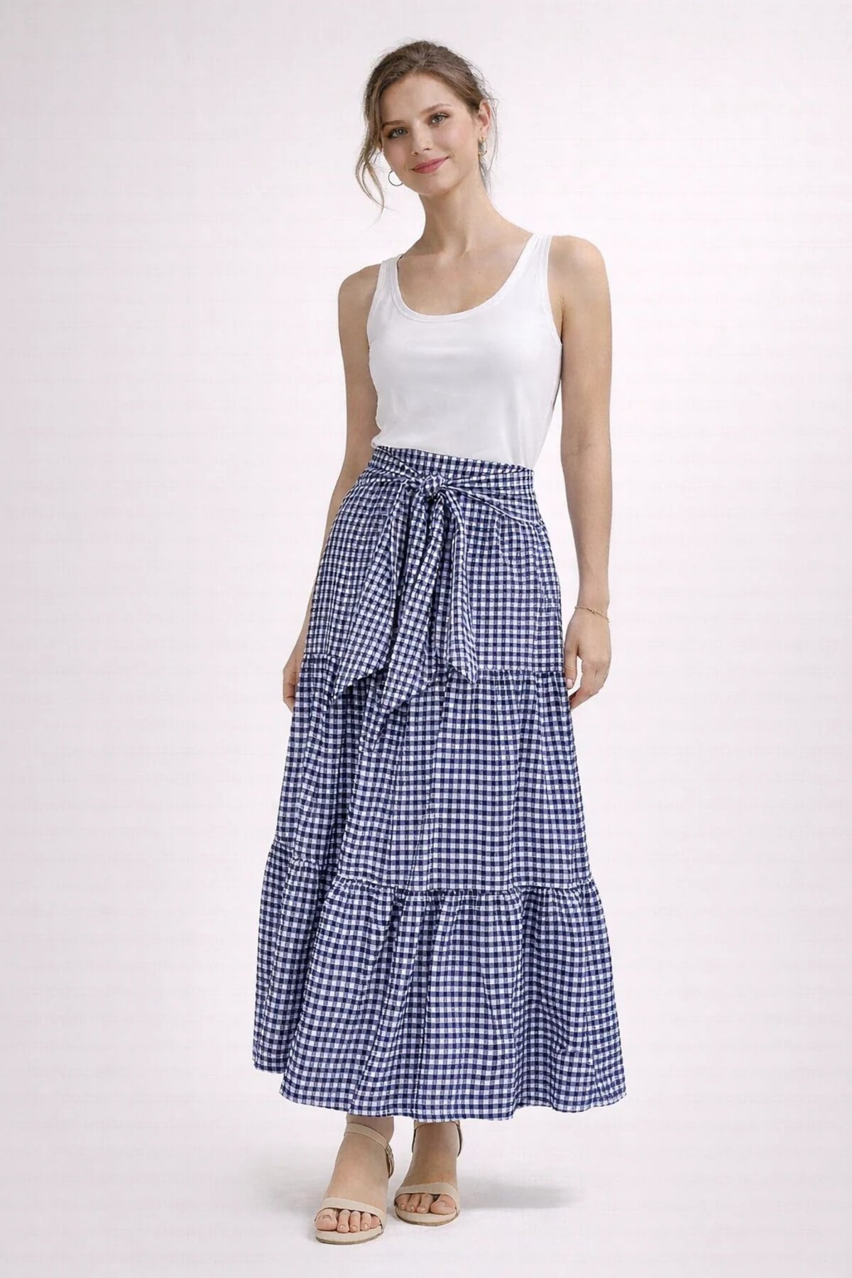 Woman wearing gingham tiered maxi skirt with tie-waist.