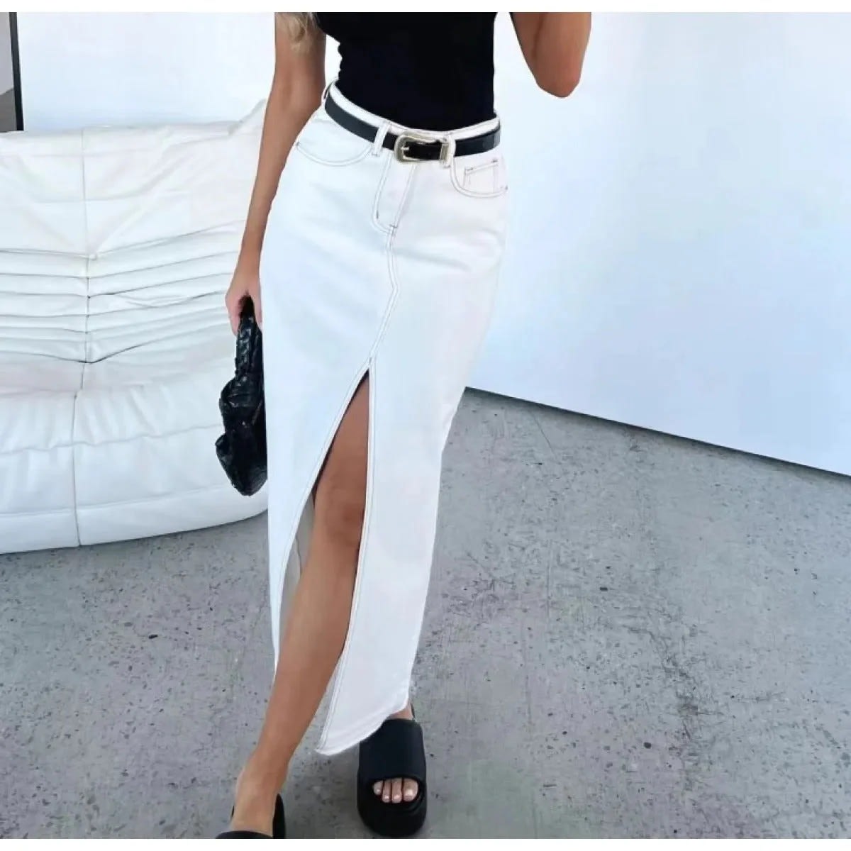 Woman wearing high-waisted denim maxi skirt with slit.