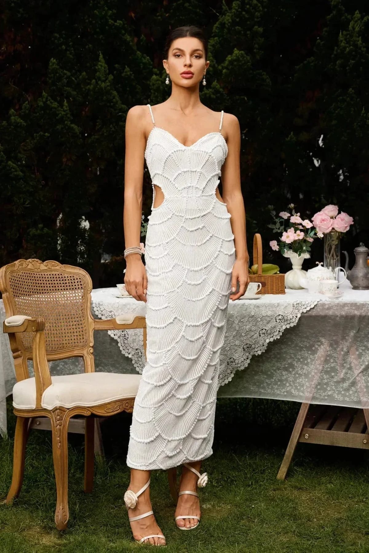 Woman in a beaded midi dress with side cut-outs and spaghetti straps.
