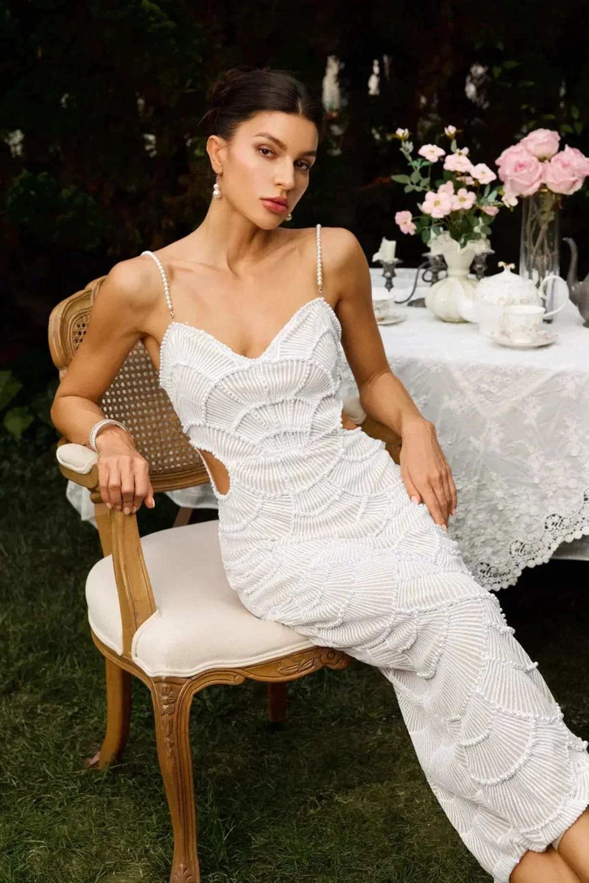 Woman in a beaded midi dress with side cut-outs and spaghetti straps.