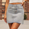 Woman wearing a denim mini skirt with button-front and raw hem.