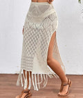 Woman wearing a crochet knit maxi skirt with high slit and fringe hem.