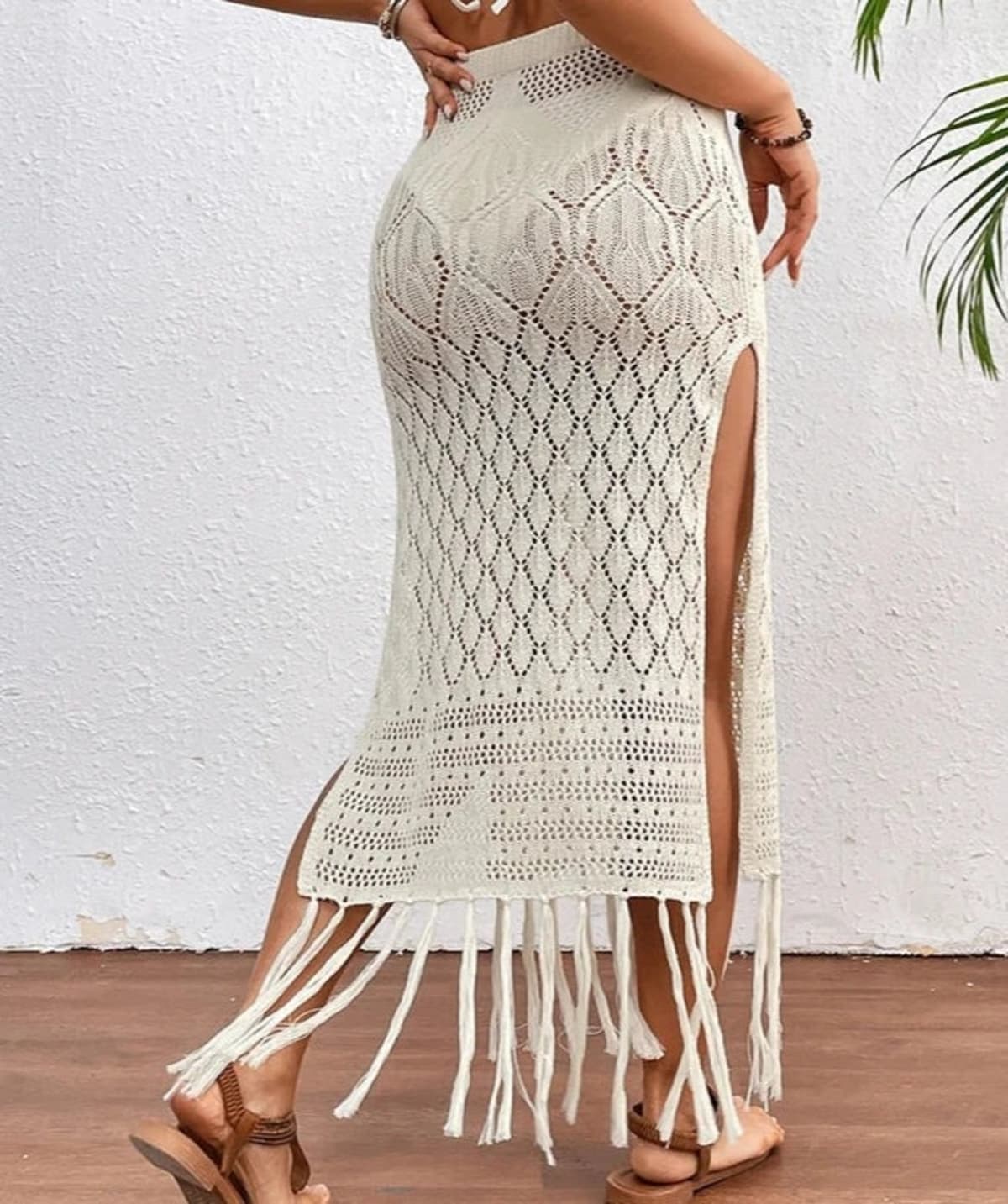 Woman wearing a crochet knit maxi skirt with high slit and fringe hem.
