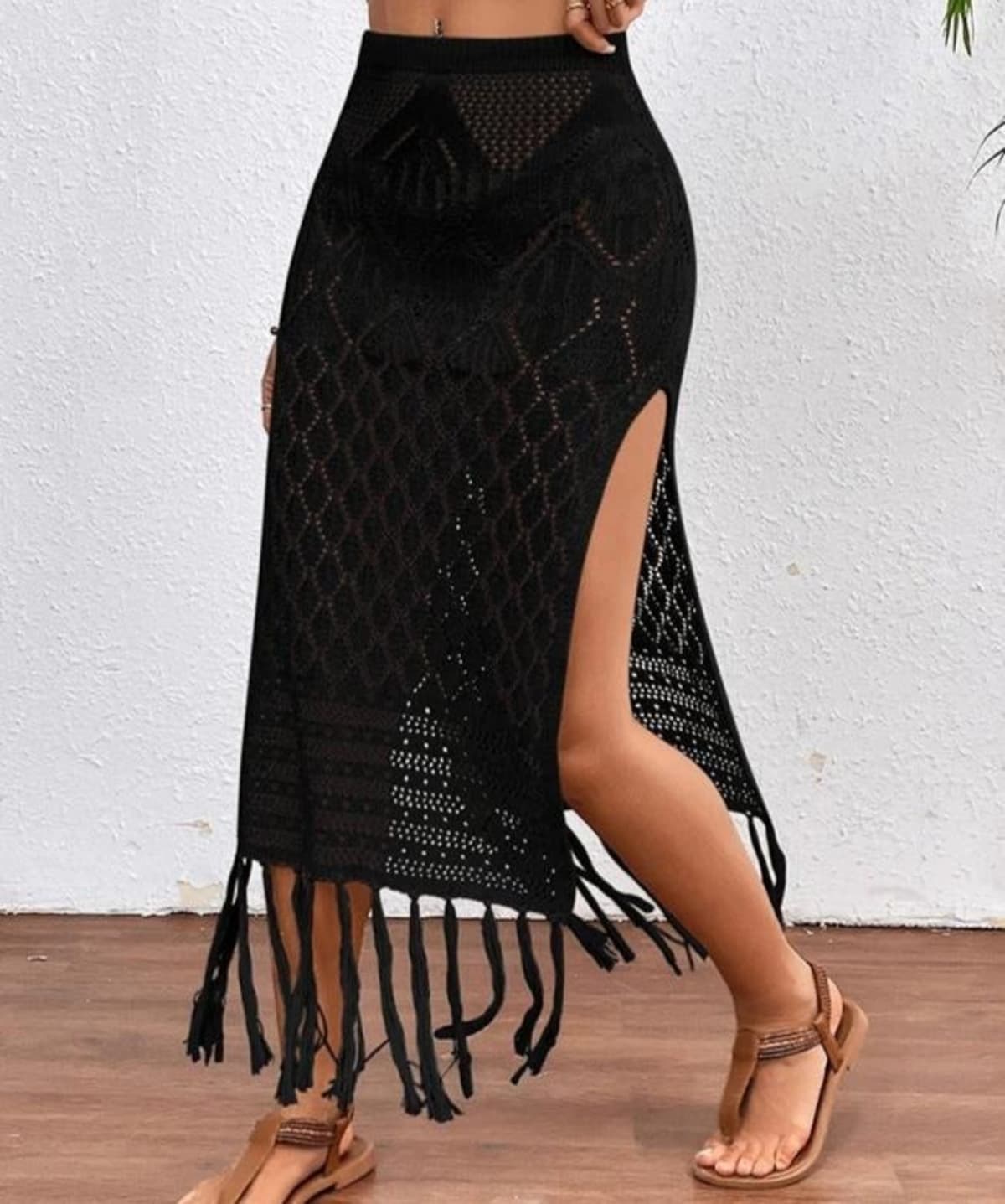 Woman wearing a crochet knit maxi skirt with high slit and fringe hem.