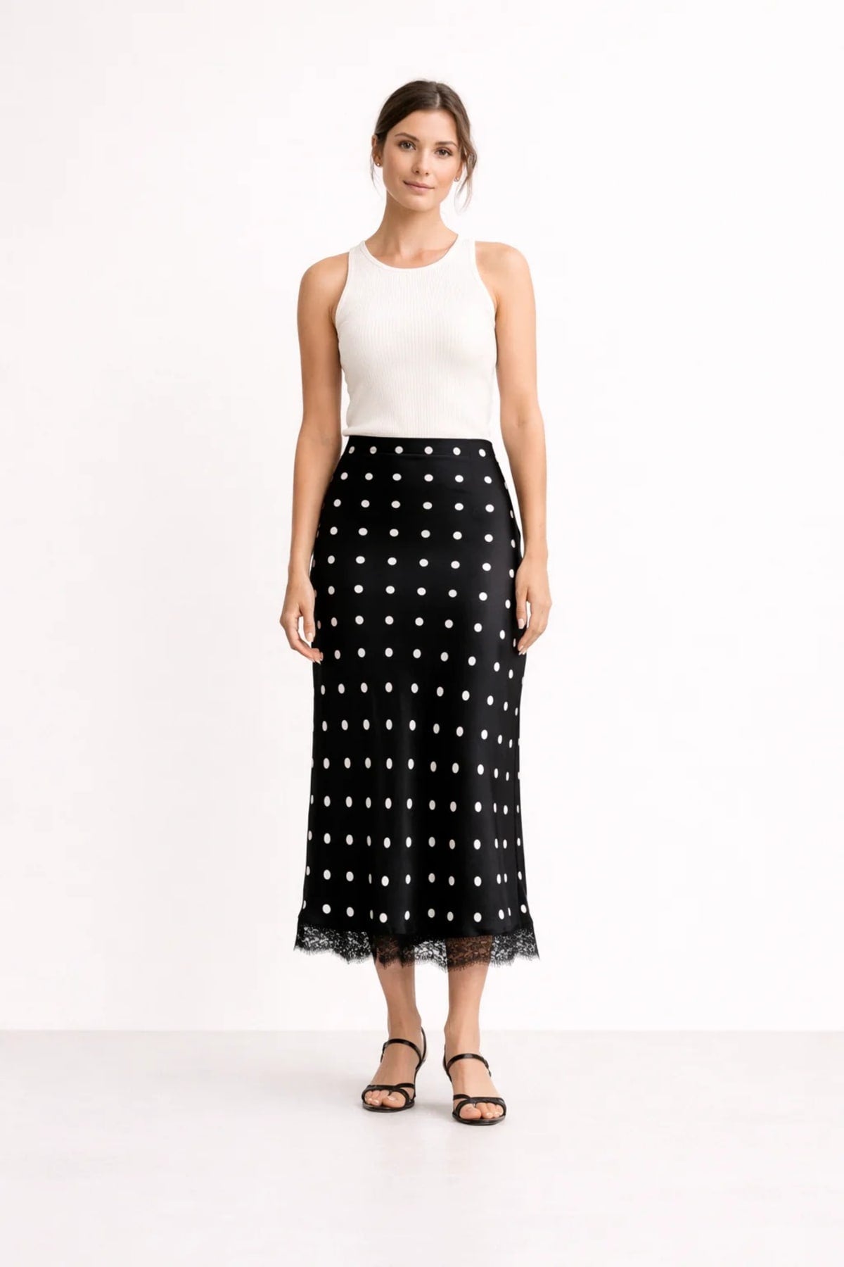 Woman wearing a midi slip skirt with polka dots and lace trim.