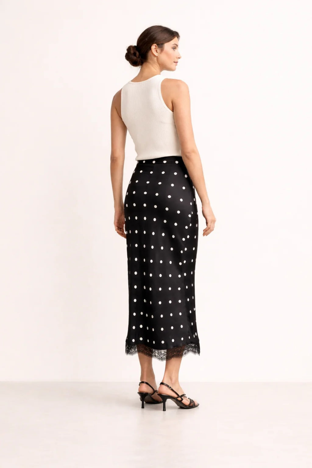 Woman wearing a midi slip skirt with polka dots and lace trim.