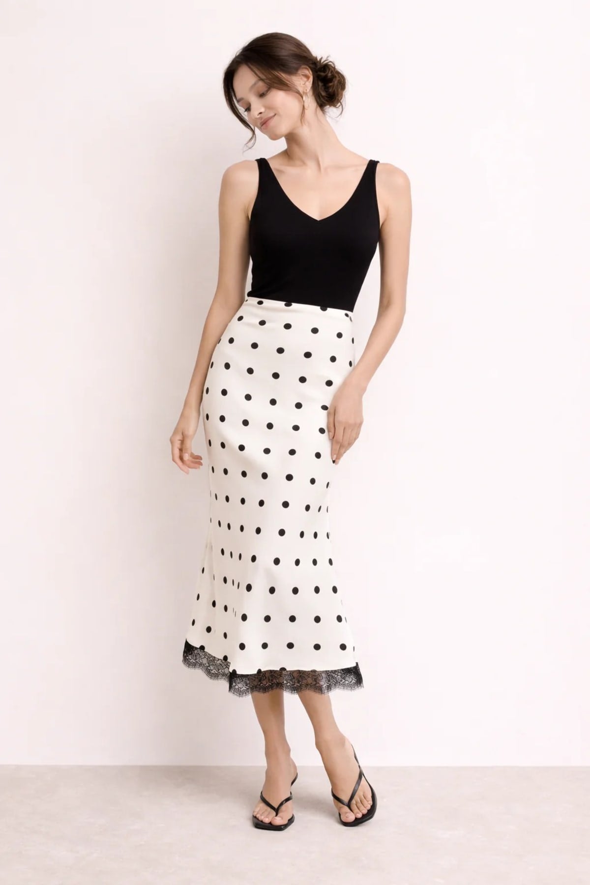 Woman wearing a midi slip skirt with polka dots and lace trim.