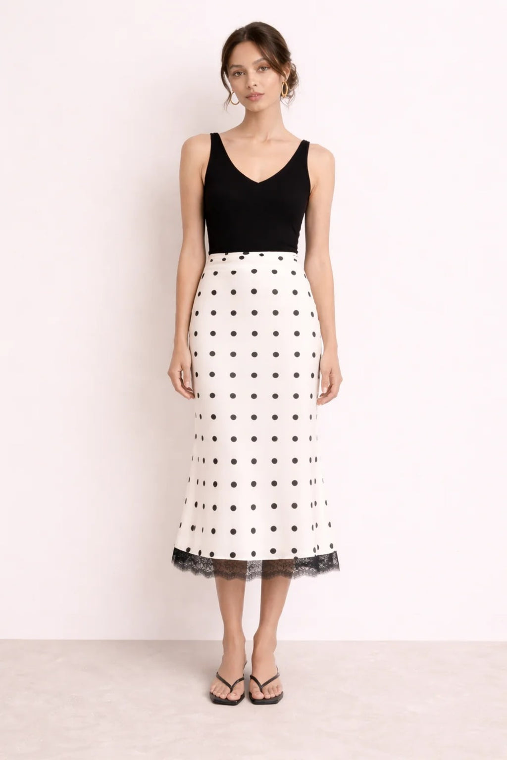 Woman wearing a midi slip skirt with polka dots and lace trim.