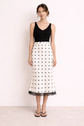 Woman wearing a midi slip skirt with polka dots and lace trim.