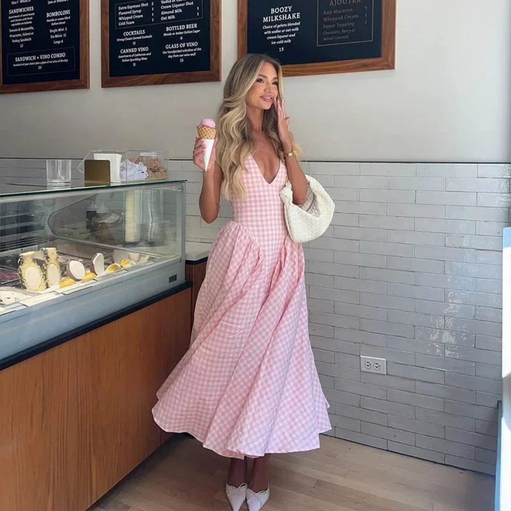 Woman wearing a gingham midi dress with V-neck and pleated skirt.