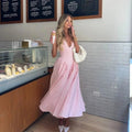 Woman wearing a gingham midi dress with V-neck and pleated skirt.