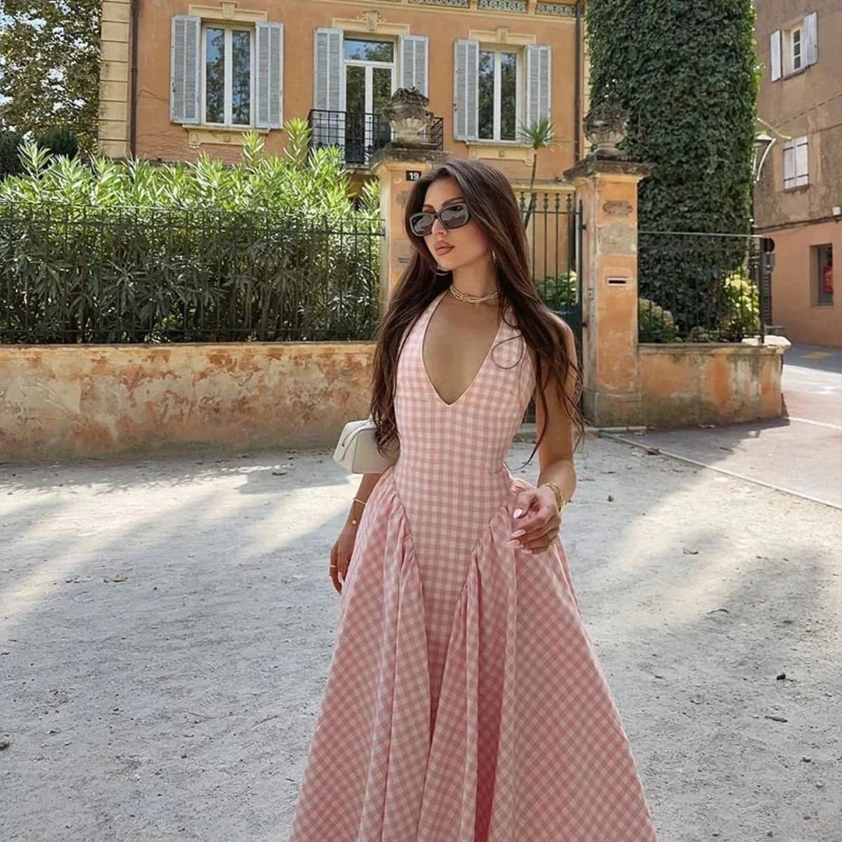 Woman wearing a gingham midi dress with V-neck and pleated skirt.