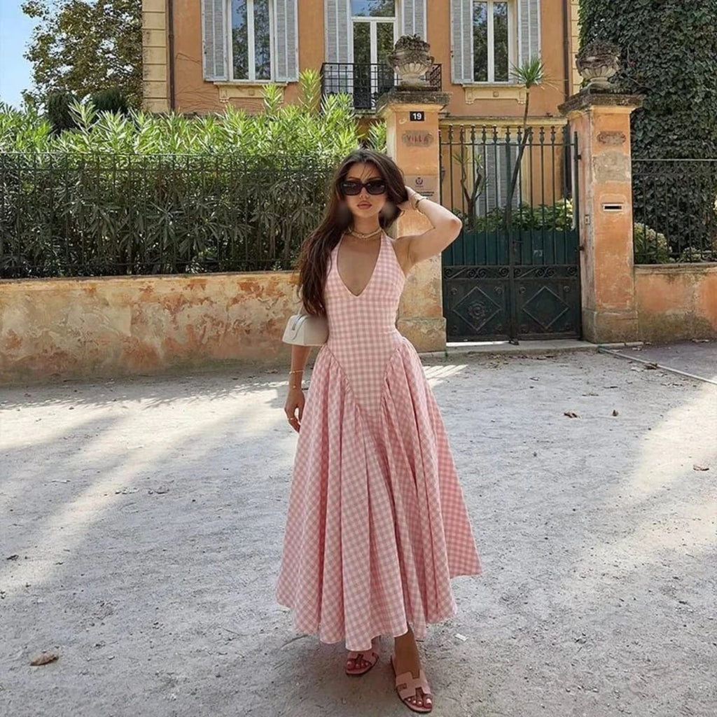 Woman wearing a gingham midi dress with V-neck and pleated skirt.