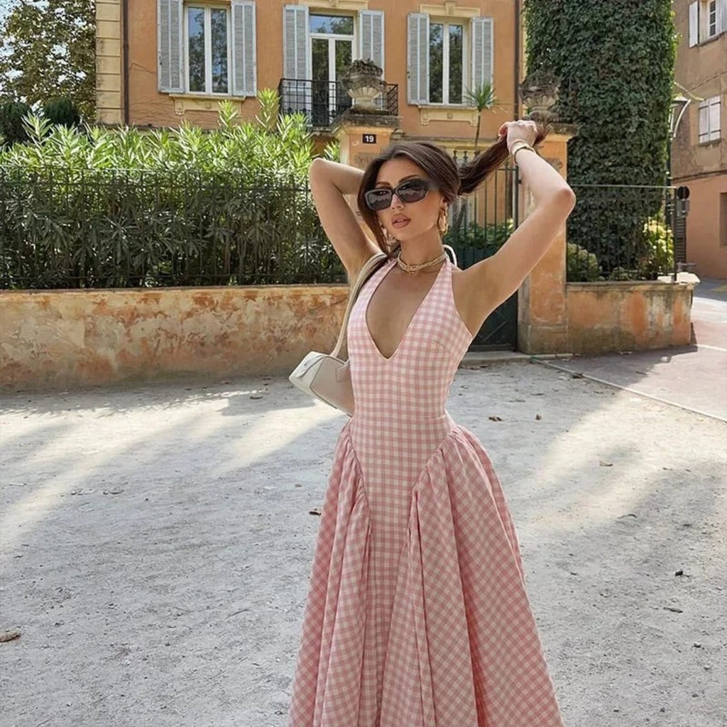 Woman wearing a gingham midi dress with V-neck and pleated skirt.
