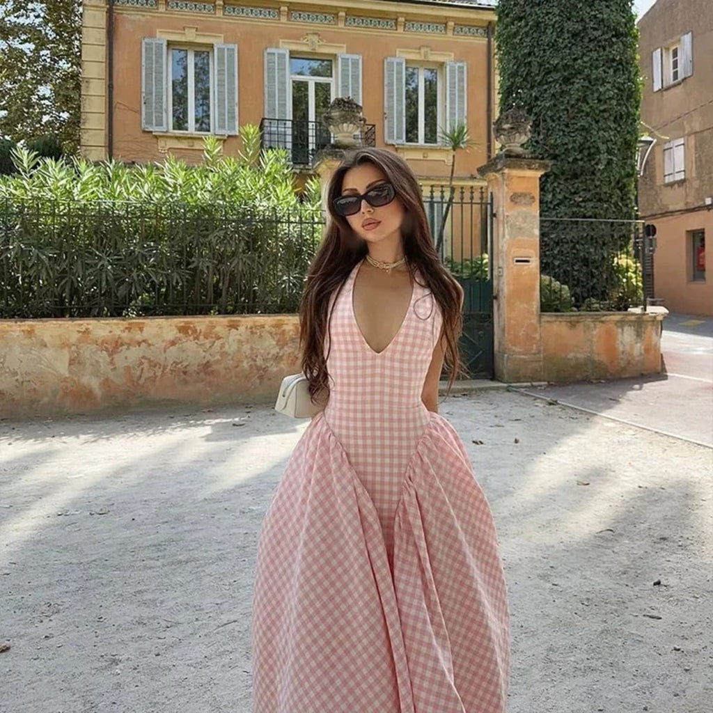 Woman wearing a gingham midi dress with V-neck and pleated skirt.