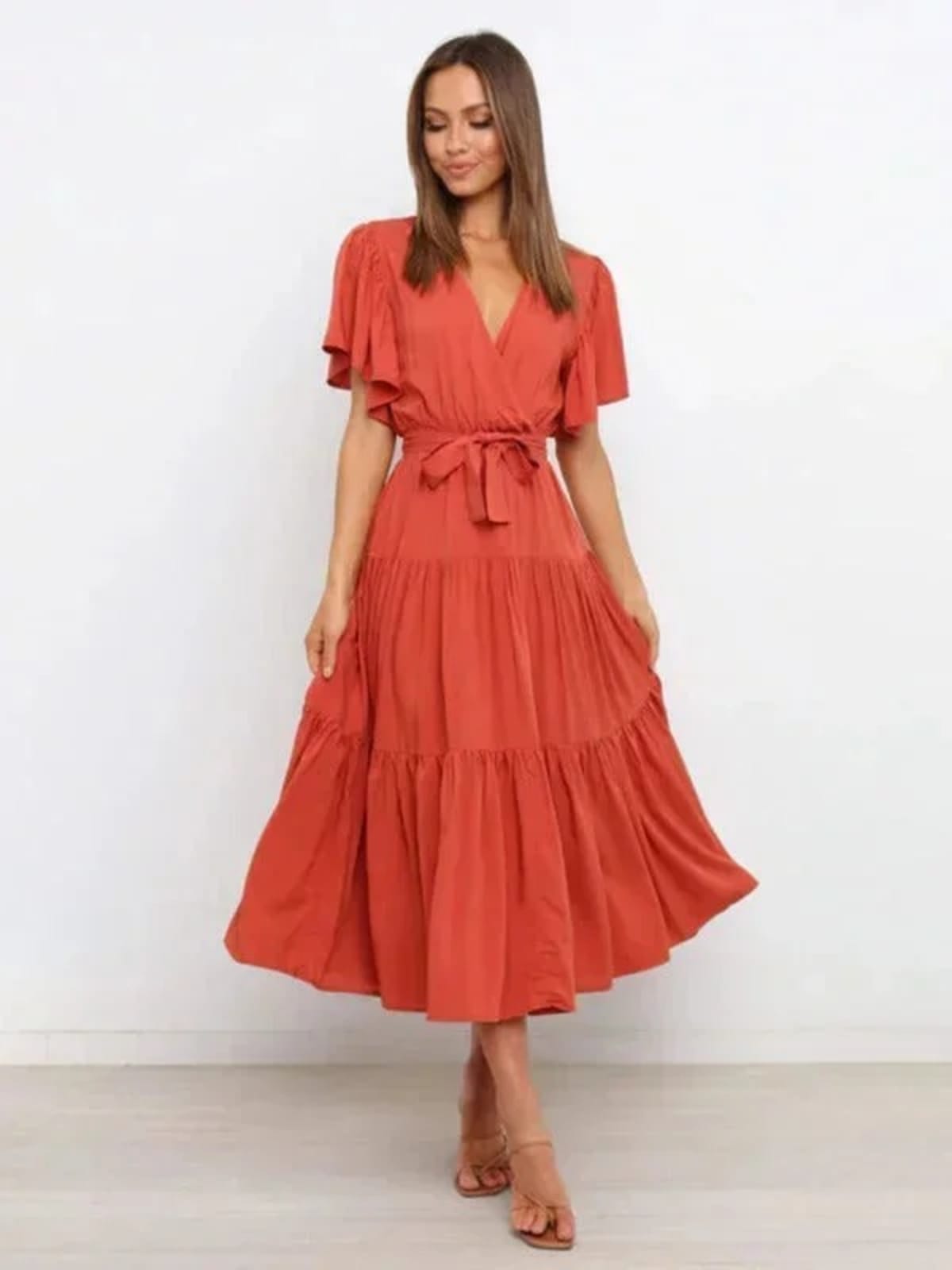 Woman in rust-colored midi dress with V-neck and tie waist.