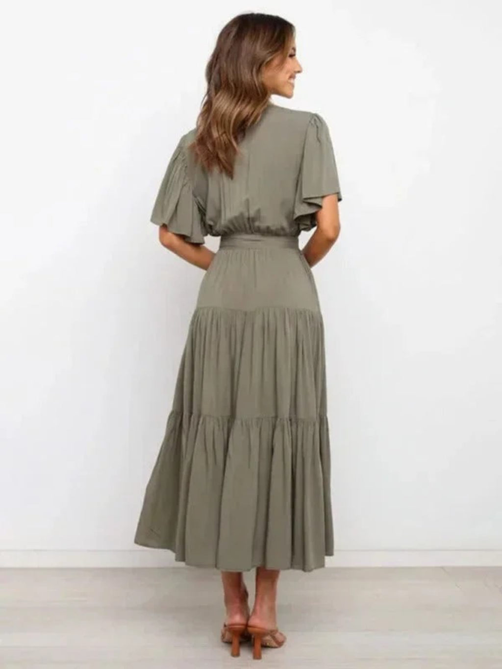 Woman in rust-colored midi dress with V-neck and tie waist.