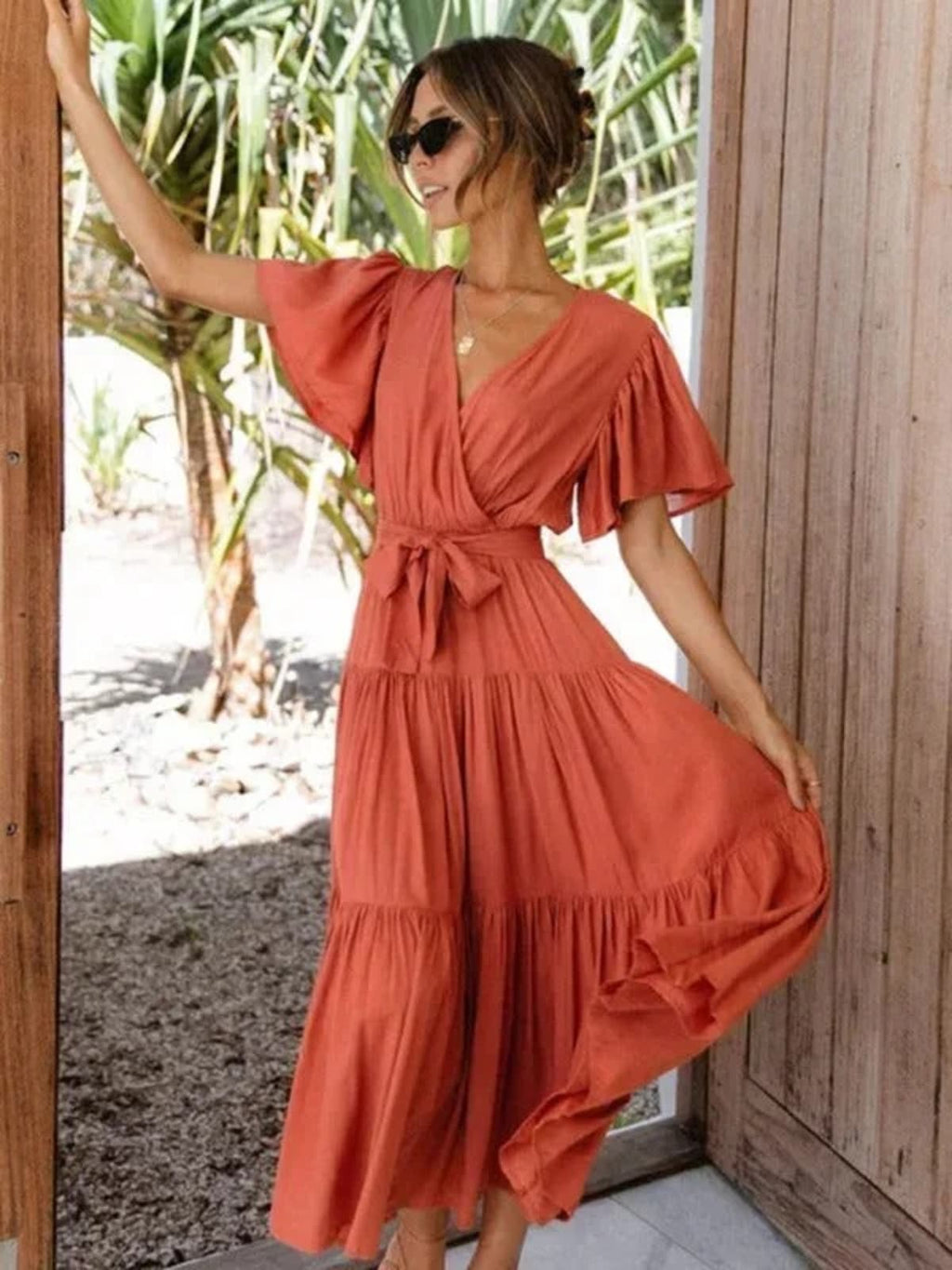 Woman in rust-colored midi dress with V-neck and tie waist.