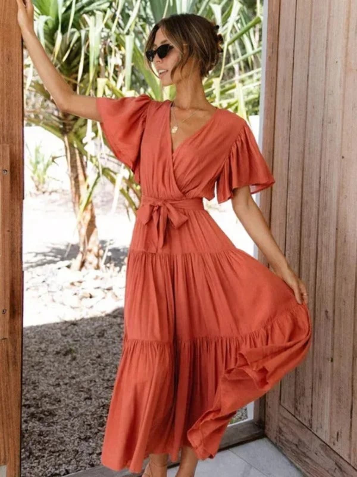 Woman in rust-colored midi dress with V-neck and tie waist.