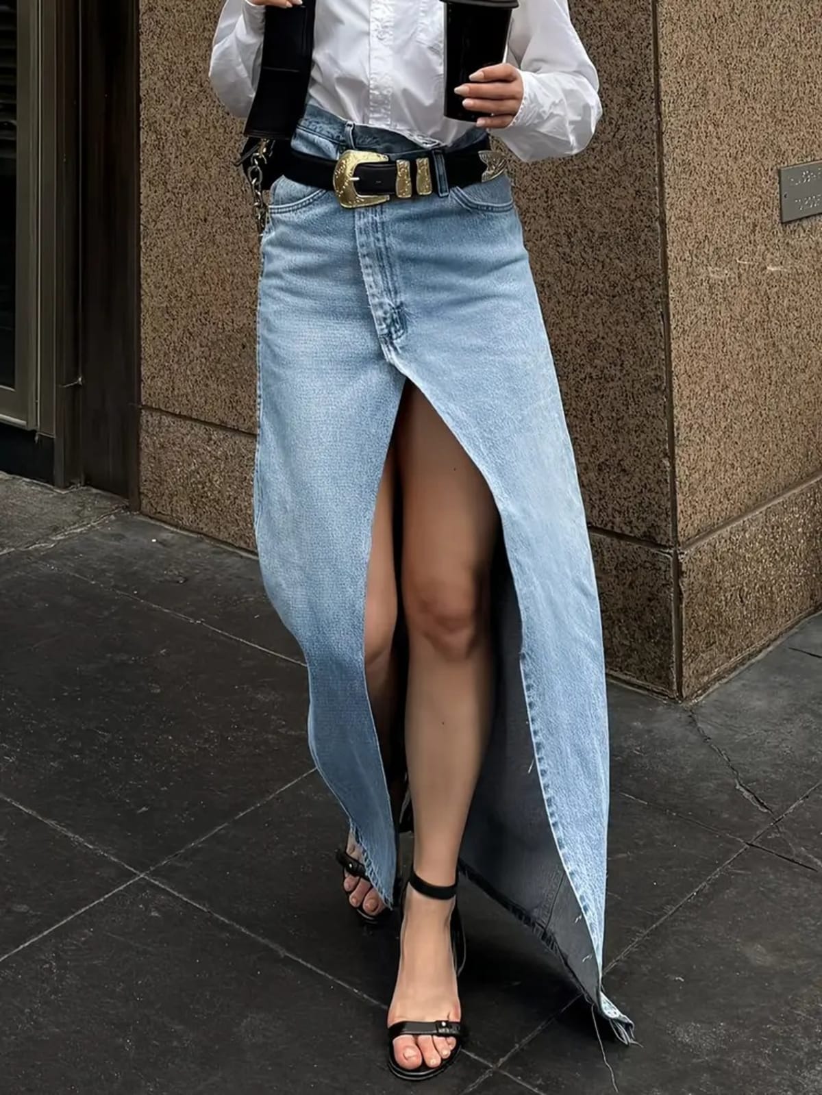 Person wearing a denim maxi skirt with high front slit and western belt.