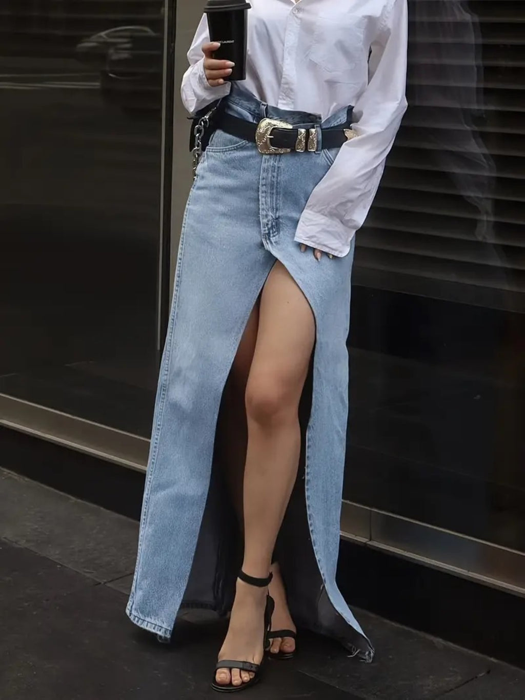 Person wearing a denim maxi skirt with high front slit and western belt.