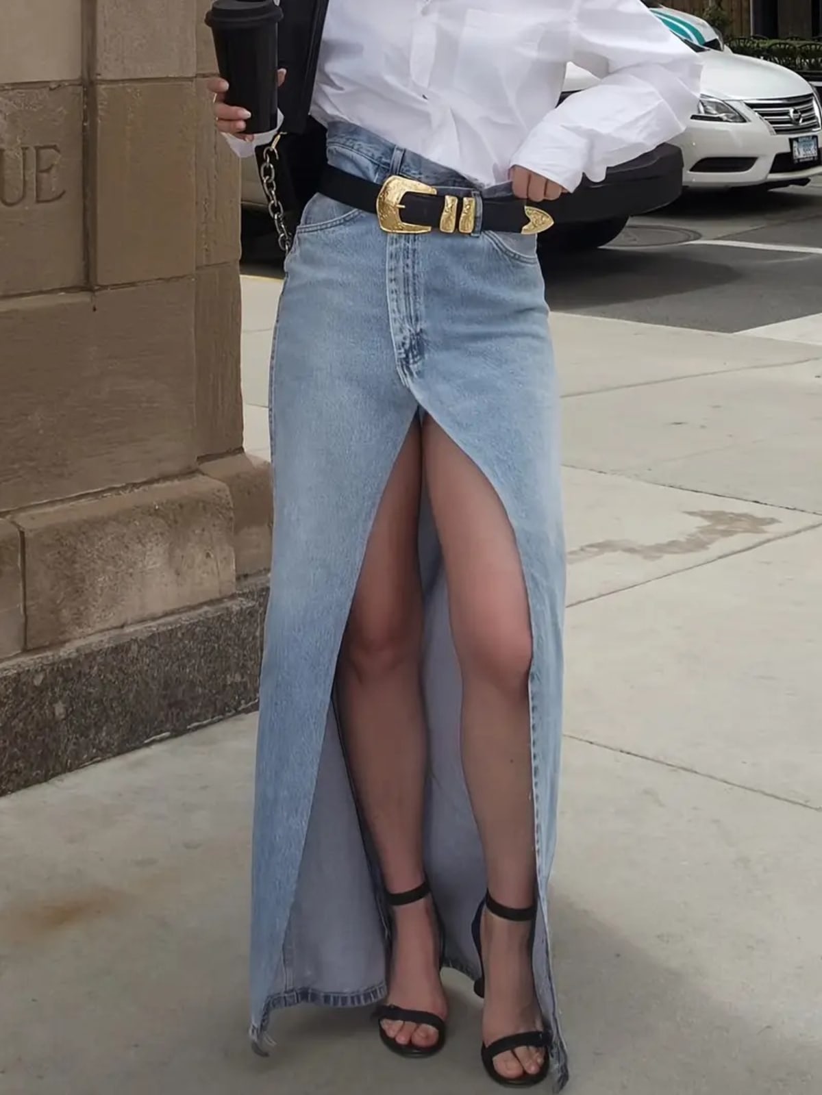 Person wearing a denim maxi skirt with high front slit and western belt.