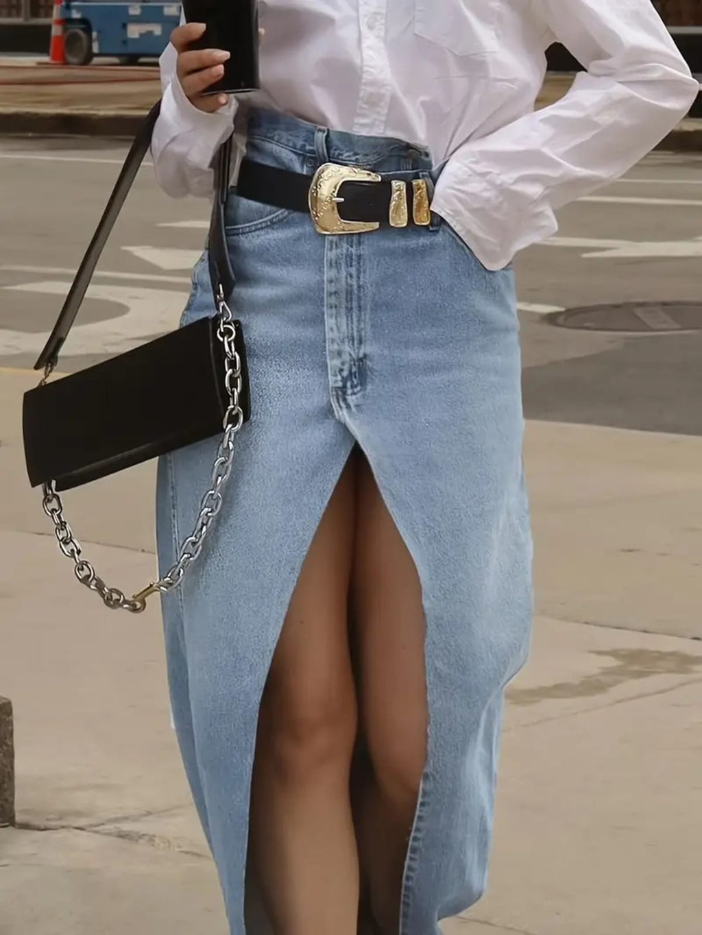 Person wearing a denim maxi skirt with high front slit and western belt.