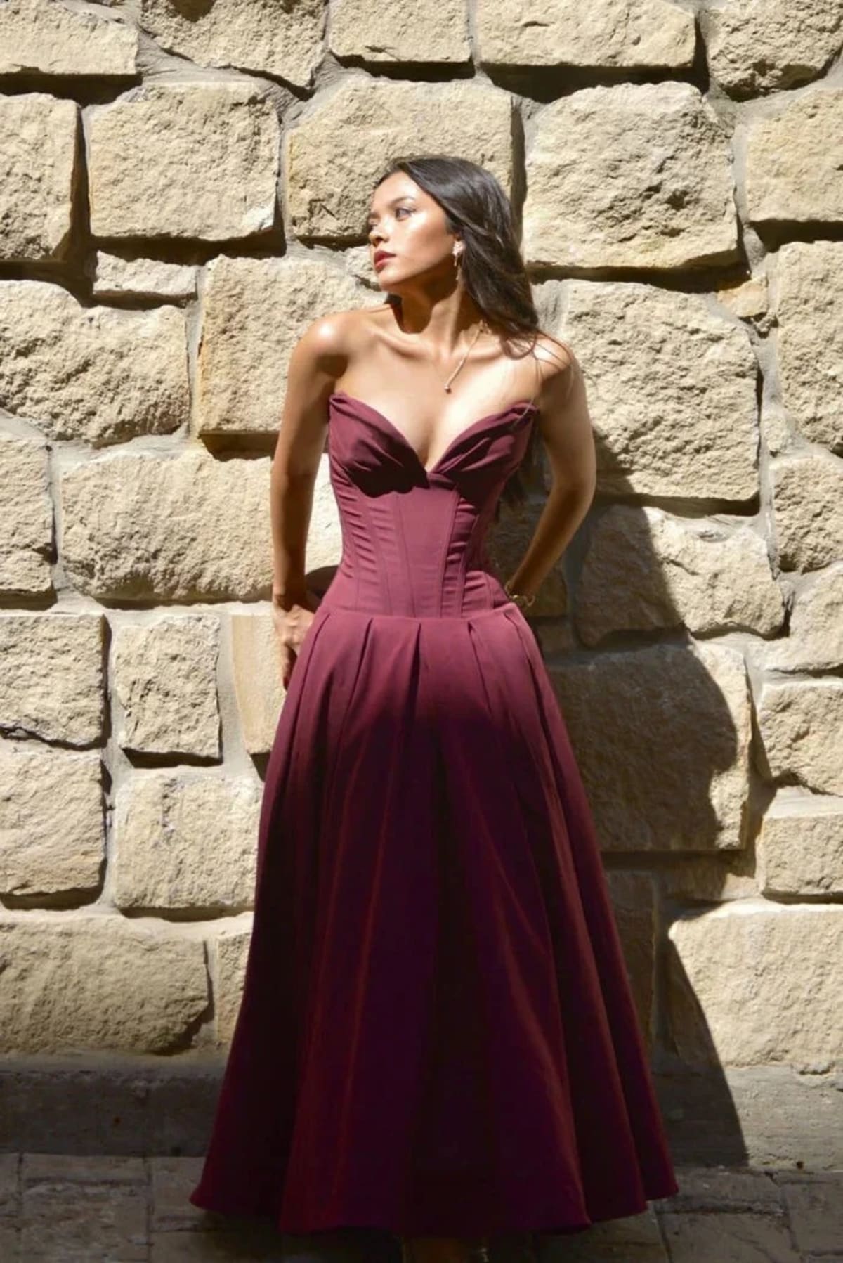 Woman modeling a strapless tea-length dress with pleated skirt.
