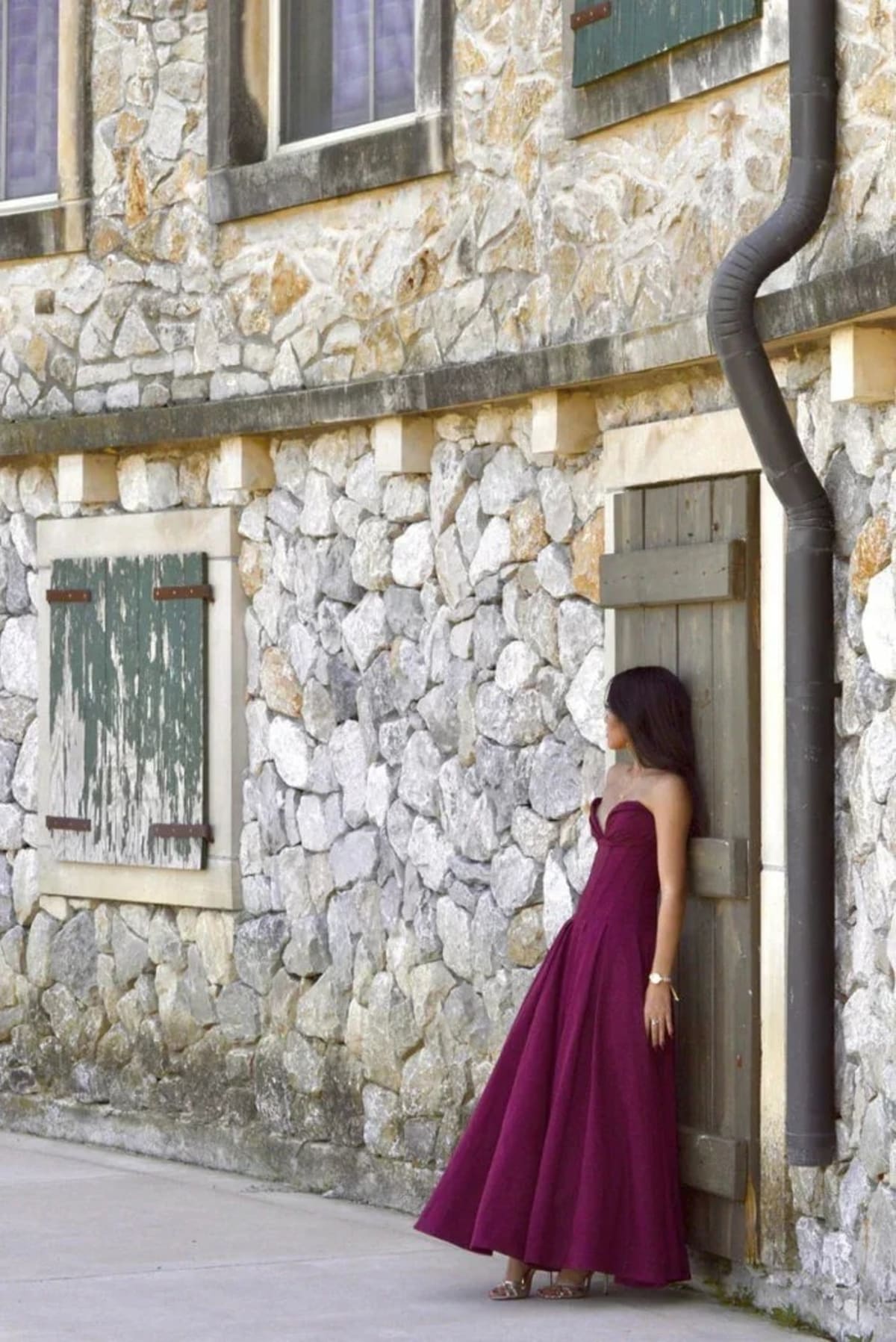 Woman modeling a strapless tea-length dress with pleated skirt.