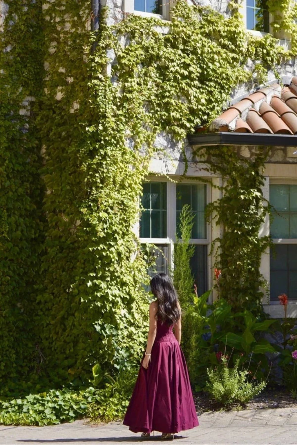 Woman modeling a strapless tea-length dress with pleated skirt.