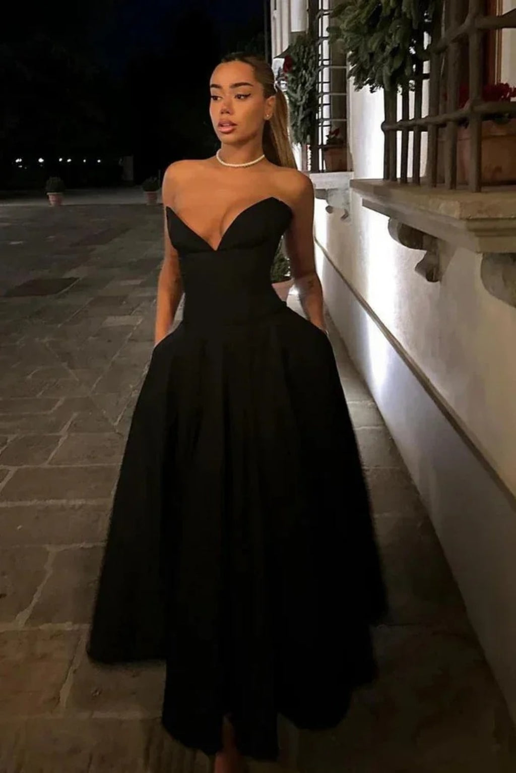 Woman modeling a strapless tea-length dress with pleated skirt.
