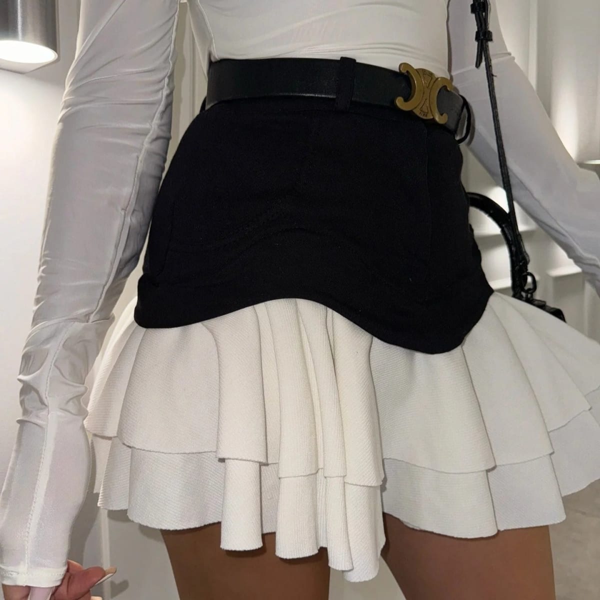 Woman in elevator wearing layered ruffle skirt with long sleeve top.