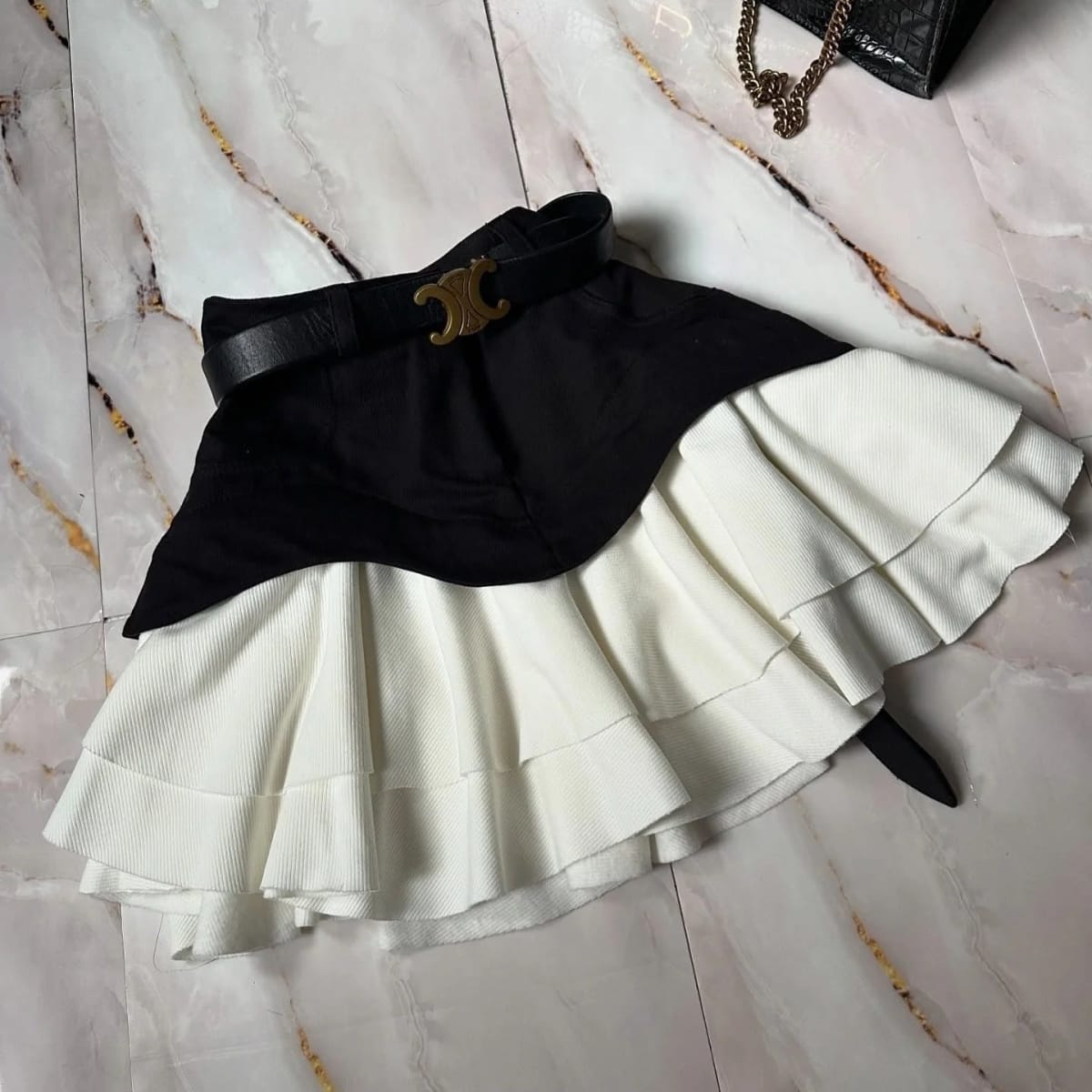 Woman in elevator wearing layered ruffle skirt with long sleeve top.