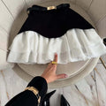 Woman in elevator wearing layered ruffle skirt with long sleeve top.
