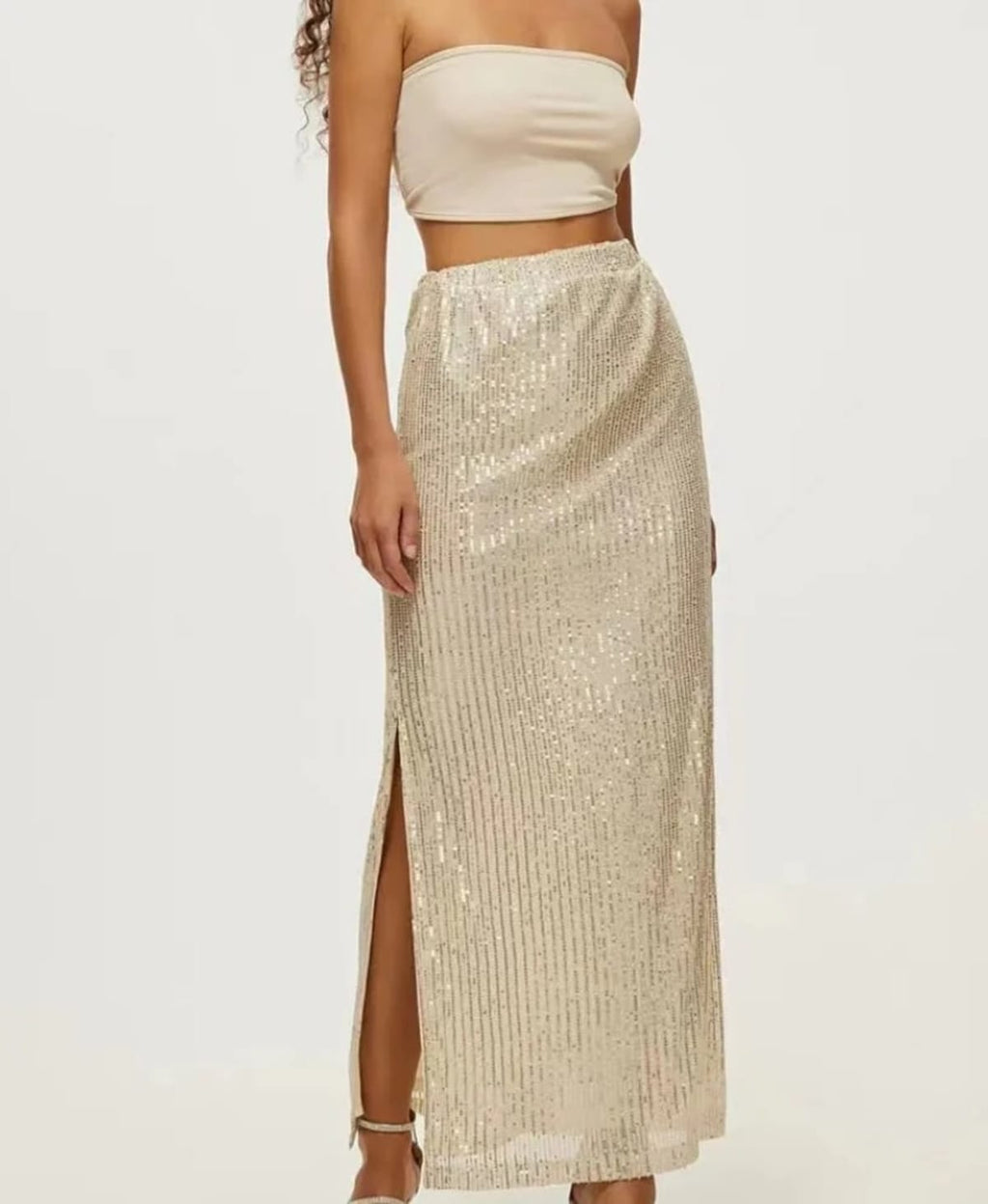 Model wearing a sequin maxi skirt with high side slit.