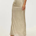 Model wearing a sequin maxi skirt with high side slit.