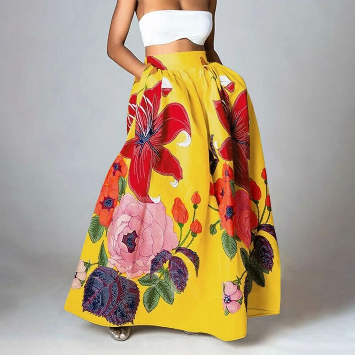 Woman wearing a vibrant floral maxi skirt with red lilies, pink peonies.