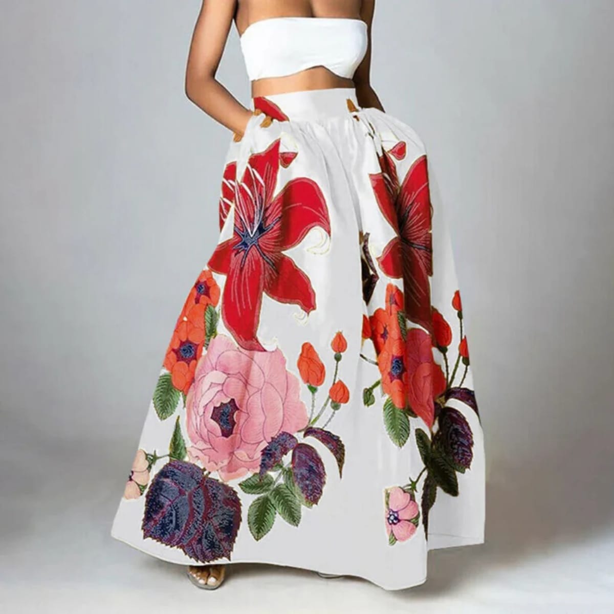 Woman wearing a vibrant floral maxi skirt with red lilies, pink peonies.