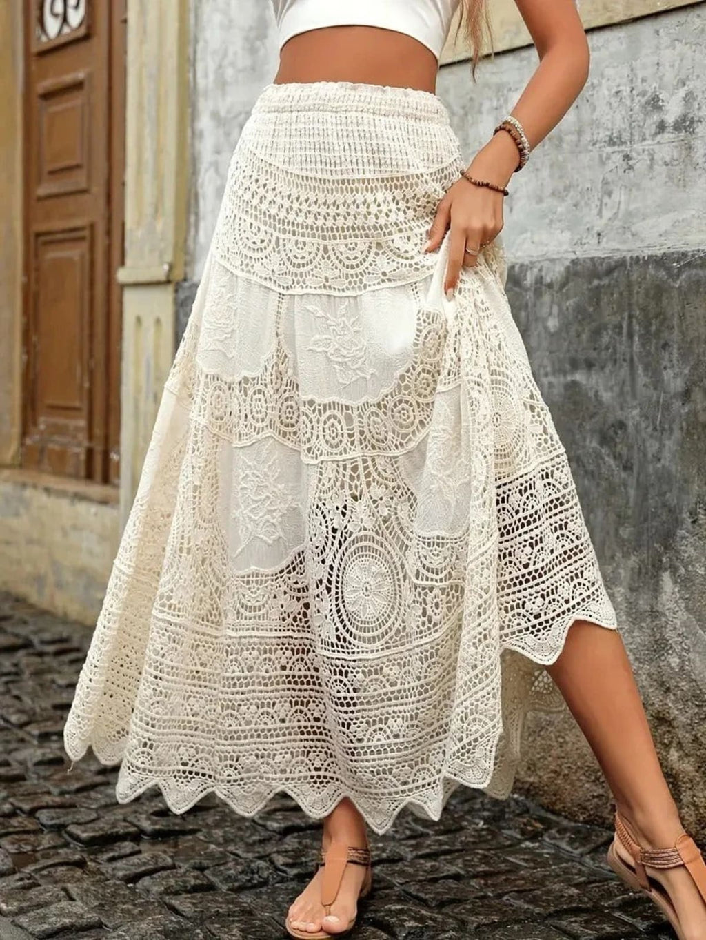 Woman sitting wearing crochet lace maxi skirt and crop top with bohemian jewelry.