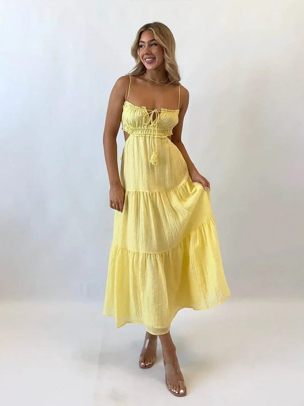 Woman in tiered midi dress with cut-outs and tassels.